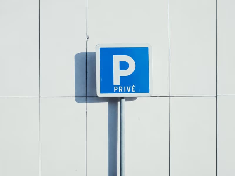 Blaues Schild «P privé» an einer weissen Hausfassade